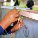 Someone sealing the IEBC ballot boxes with green tapes.