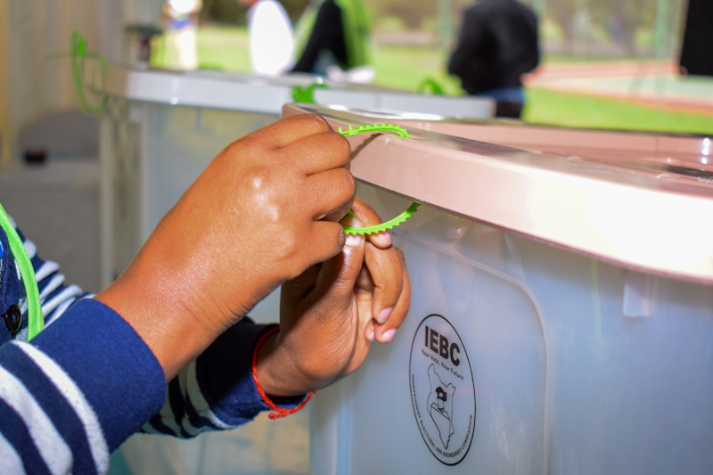 Someone sealing the IEBC ballot boxes with green tapes.