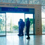 Image of the exit sliding doors at bole international airport with a large banner at the side saying "WELCOME" And another one at the top saying "Have a pleasant time in your motherland, Ethiopia".