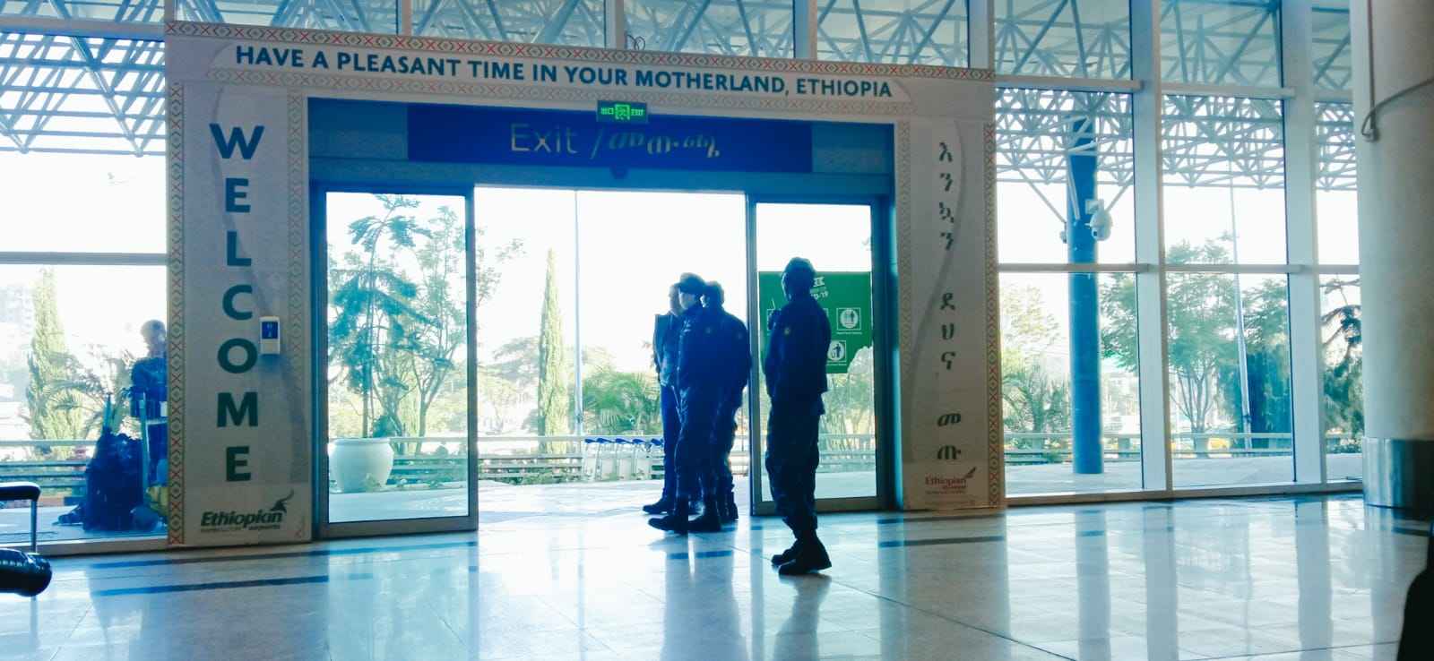 Image of the exit sliding doors at bole international airport with a large banner at the side saying "WELCOME" And another one at the top saying "Have a pleasant time in your motherland, Ethiopia".