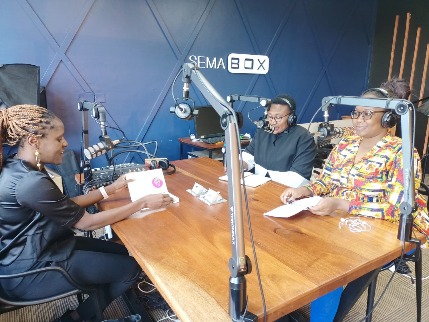 Liz Orembo, Anita Epalle and Mylline Anunda in a studio recording a podcast.