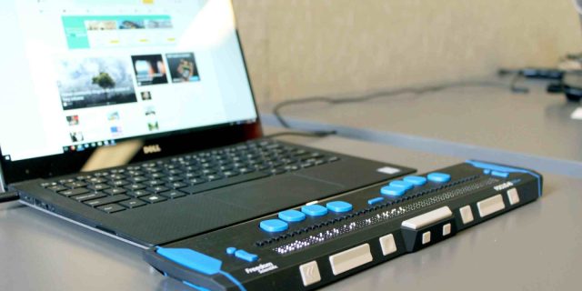 A braille computer with blue tabs and an open screen