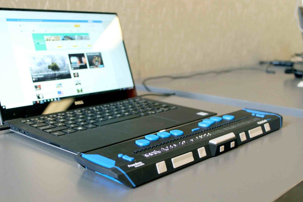 A braille computer with blue tabs and an open screen