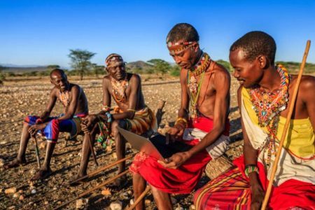 African warrior from Samburu tribe using laptop on savanna, central Kenya, Africa. Samburu tribe is one of the biggest tribes of north-central Kenya, and they are related to the Maasai.
