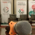 A microphone on a podium against a blurred background of KeIGF2023 banners