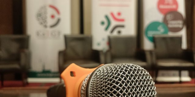 A microphone on a podium against a blurred background of KeIGF2023 banners