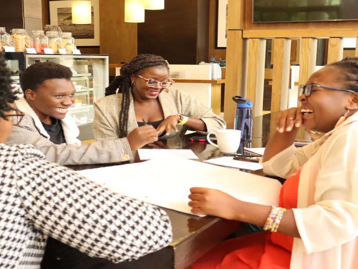 women sitting around a table with pens and papers. They are all laughing