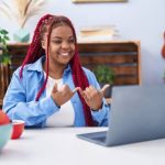 A lady using sign language infront of a laptop