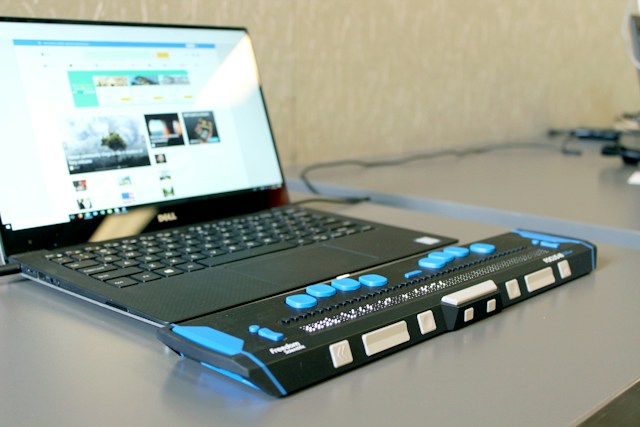 A laptop on a table attached to a braille keyboard
