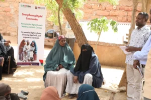 A vibrant community gathering in Mandera County with people of various ages engaging in a digital skills training session under the Strengthening Digital Communities Project.